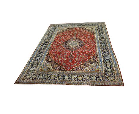 Large Tabriz carpet, with large central medallion in cream and navy against a crimson field with allover flower design, enclo