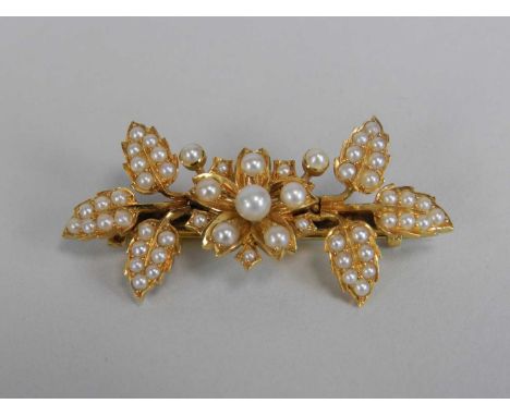A seed pearl set bar brooch, designed as a central floral cluster flanked to each side by trefoil leave sprigs, 46mm wide, no