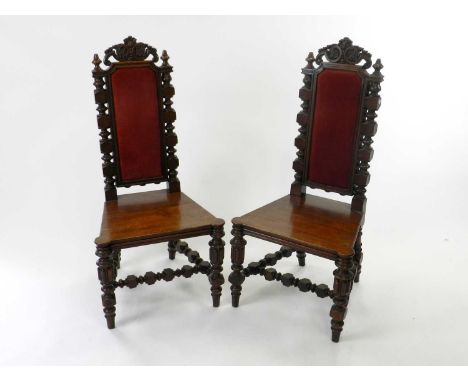 A pair of 19th Century carved oak Flemish style high back side chairs, the upholstered backs with scroll crestings, the plain