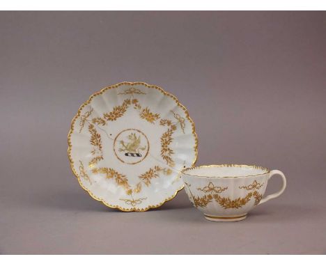 A Worcester teacup and saucer circa 1785-90 of fluted form, painted with a griffin crest and gilded floral swags with a denti