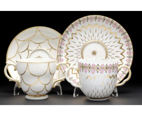 TWO DERBY PINEAPPLE MOULDED OR OGEE CHOCOLATE CUPS AND STANDS, ONE WITH GREEN, PUCE AND PURPLE BERRY BORDER, THE OTHER GILT, 