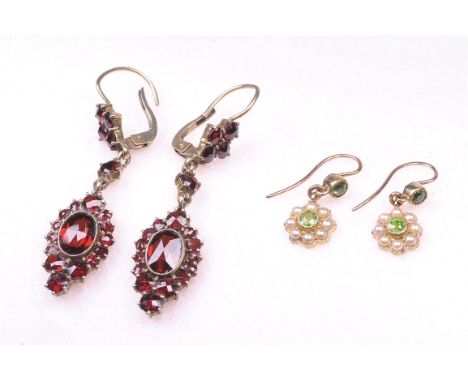 A pair of split pearl and peridot set ear pendants, circa 1910-1920
Each having a central round cut peridot, milgrain set to 