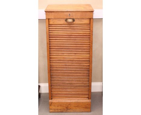 An early 20th Century light oak filing cabinet, sliding trays enclosed tambour shutter, 18" wide