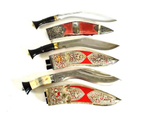 Three Presentation Kukris, one with polished bone grip, two with polished horn grips, each in a silver mounted scarlet velvet