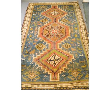 A Persian hand woven wool carpet with three central medallions on a red field, with decoration of stylised birds and animals,