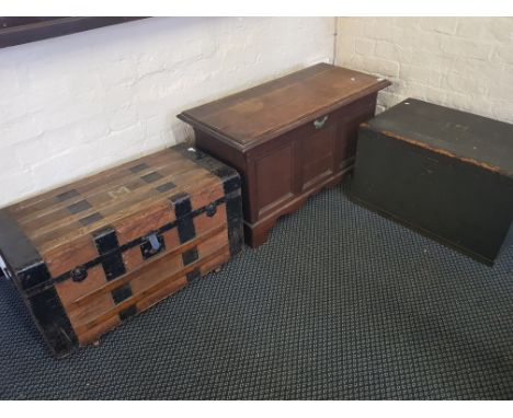 An oak blanket chest with three panel front, stained wood storage box and a metal edged travel trunk.