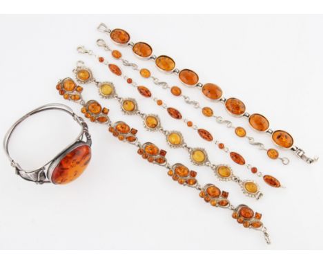 A collection of five clarified amber bracelets, all stamped 925, together with a clarified amber bangle, featuring an oval am