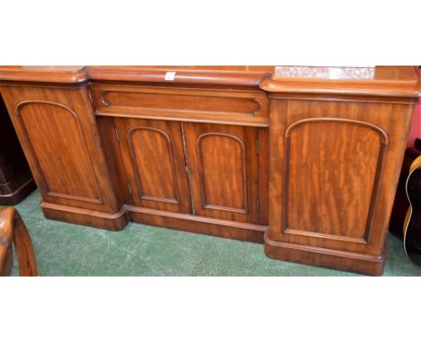 A Victorian mahogany inverted break centre sideboard, rounded top above a central drawer and a pair of panel doors enclosing 