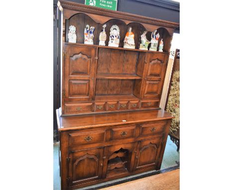 A Country house oak dresser, dentil cornice above three plate racks flanked by a pair of raised and fielded panel doors above