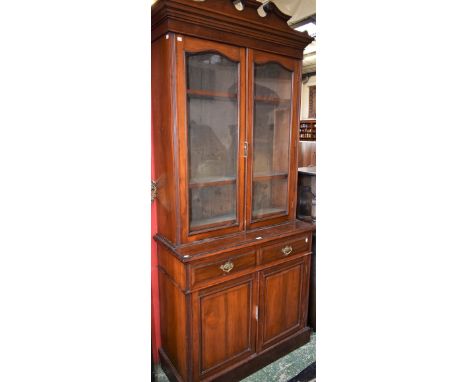 An early 20th century mahogany library bookcase, swan neck pediment above a pair of glazed doors enclosing three adjustable s