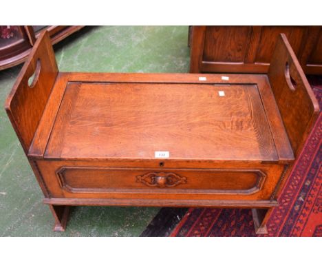 An oak combination blanket chest window seat, hinged seat flanked by carry handles above an elongated octagonal panel applied
