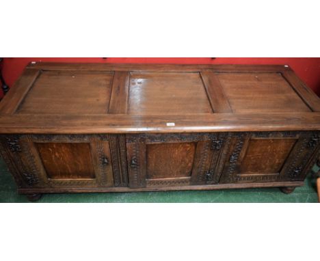 A 17th century style oak low side cabinet, styled as a blanket chest, three panel top above three panel doors applied with st