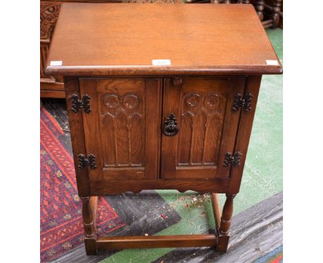 An oak hall cupboard, oversailing rectangular top above a pair of Gothic moulded panel doors, shaped apron, turned supports, 
