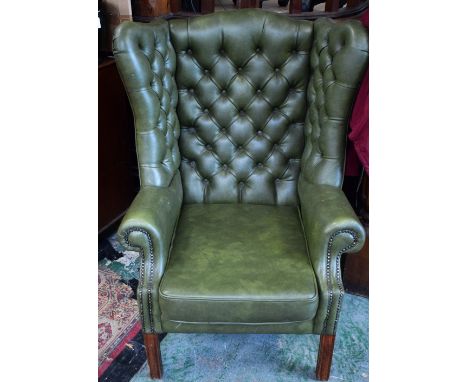 A Chesterfield type wingback armchair, deep button back, scroll arm, square forefeet