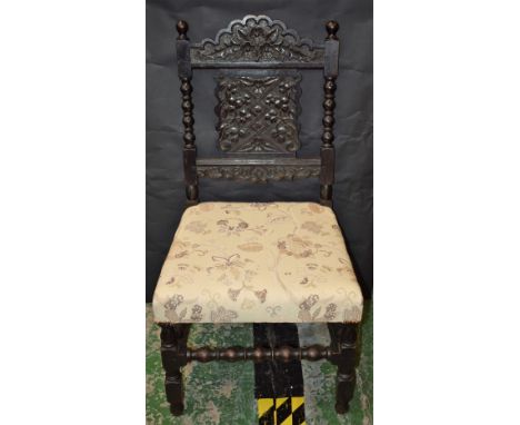 An 18th century style oak side chair, of broad and deep proportions, shaped back carved with flowerheads and scrolling leaves