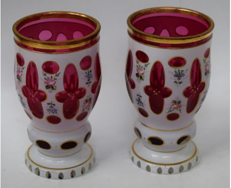 A pair of late 19th century Bohemian ruby glass vases, overlaid in white and painted flowers, banded in gilt, 14.5cm high, c.