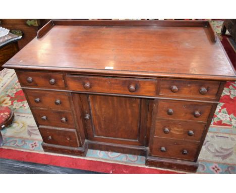 A Victorian mahogany writing desk, moulded rectangular top with shallow gallery above an arrangement of drawers and a central