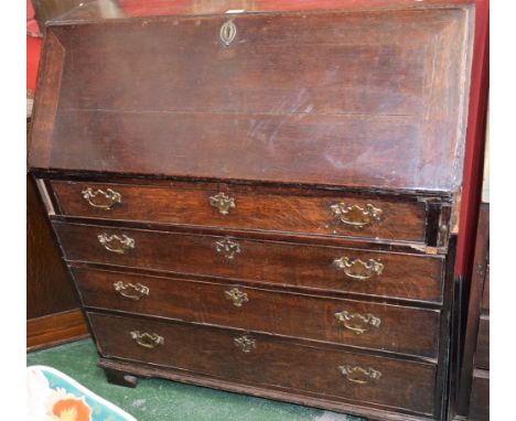 A George III oak bureau, fall front enclosing an arrangement of small drawers, a small cupboard door and pigeon holes above f