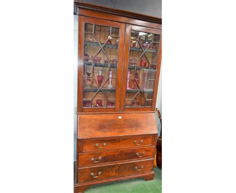A George III style mahogany bureau bookcase, outswept dentil cornice above a pair of astragal glazed doors enclosing three ad