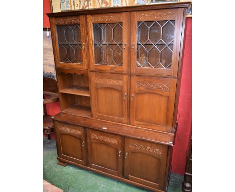 A New Plan Furniture oak side cabinet, outswept cornice above an arrangement of open, glazed and panel compartments, the base