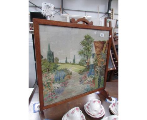 An oak fire screen with embroidered panel.