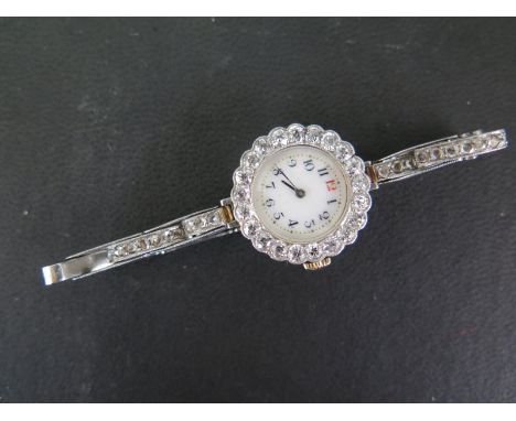 A Lady's manual wind watch with round white black Arabic dial unsigned, with bezel set with twenty one round early brilliant 