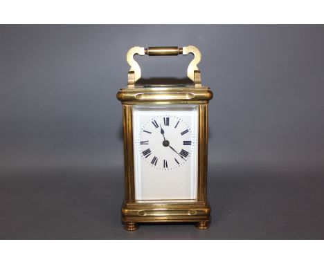 An early 20th century Carriage clock, full face white enamel dial with Roman numerals, the top of the gilt brass case engrave