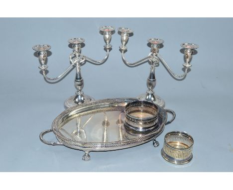 A PAIR OF SILVER PLATED THREE LIGHT CANDELABRA, together with two plated bottle coasters and an oval twin handled tray (5)