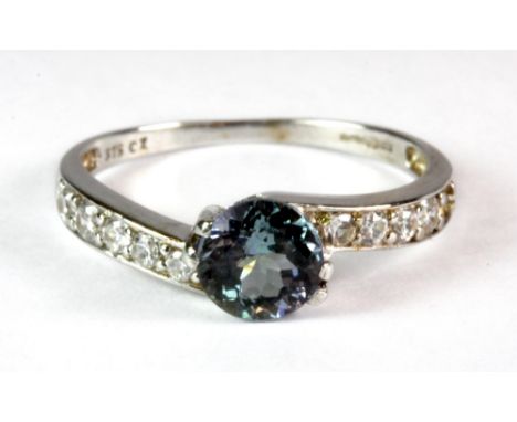 A lovely 9ct white gold ring set with a central brilliant cut light tanzanite and stone set shoulders (L.5).