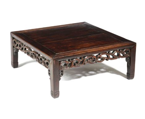 A CHINESE HARDWOOD LOW TABLELATE 19TH CENTURYthe panelled top above a pierced scrolling frieze on scroll feet28cm high, 68cm 