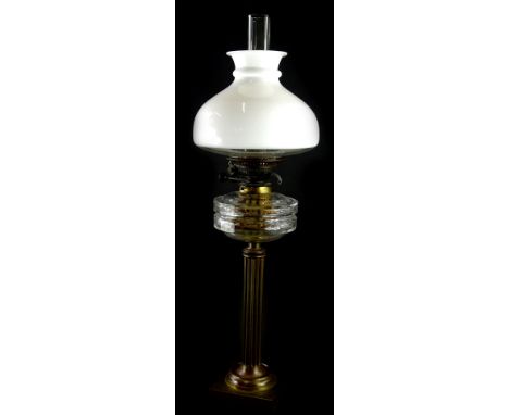 A Victorian brass effect oil lamp, with a facetted glass reservoir, 47cm high and an opaque shade with funnel.