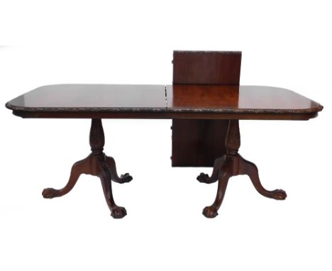 A mahogany two pillar dining table in George III style, the rectangular with rounded corners and a carved border, on turned a