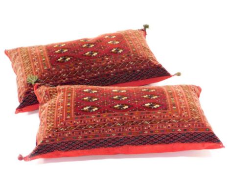 A near pair of large rectangular Belouch carpet cushions, with a design of medallions on a red ground with numerous borders, 