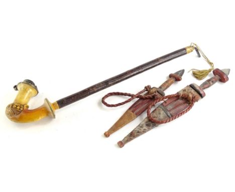 A continental Meerschaum carved pipe, with wooden handle, 50cm long, and two African daggers, with leather handle and scabbar
