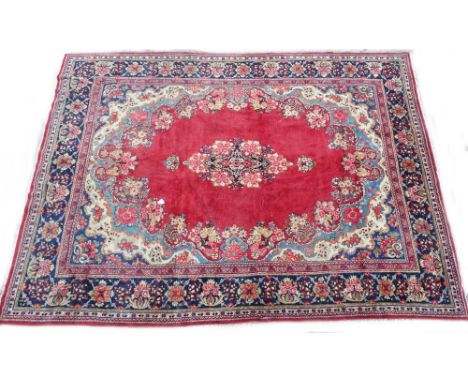An Eastern carpet, with a central floral medallion, on a red ground with multi-coloured spandrels, one wide and various narro
