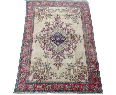 An Indian carpet, with a central rococo scroll and flower medallion in lime green, on a beige ground with one wide and two na