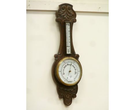 Edwardian aneroid barometer with thermometer in carved oak surround, H82cm