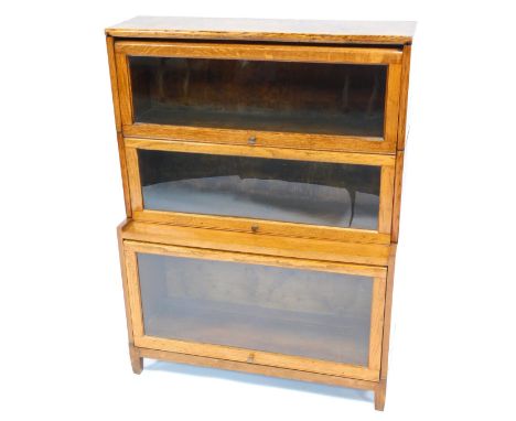 A Globe Wernicke style oak three section bookcase, with up and over glass doors, raised on square feet, 115cm high, 87cm wide