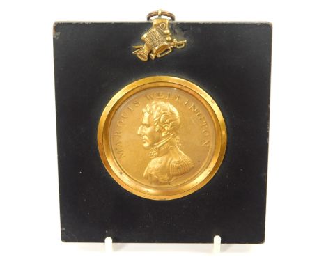 A Marquis of Wellington reproduction portrait plaque, cast in ebonised frame, with drum cannon and sword moulded hanging hook