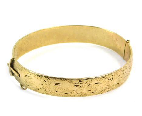 A hinged bangle, of floral scroll design, stamped 9ct RG, 6cm diameter.