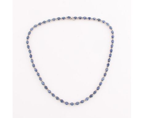 A contemporary sapphire and diamond necklet, comprising of 55 oval cut sapphires, each measuring approx. 5x4mm, with two roun