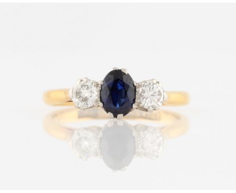 A sapphire and diamond three stone ring, set with a central oval cut sapphire, measuring approx. 6x4mm, flanked to either sid