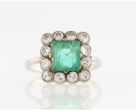 An emerald (possibly synthetic) and diamond cluster ring, set with a central square cut emerald (possibly synthetic), surroun