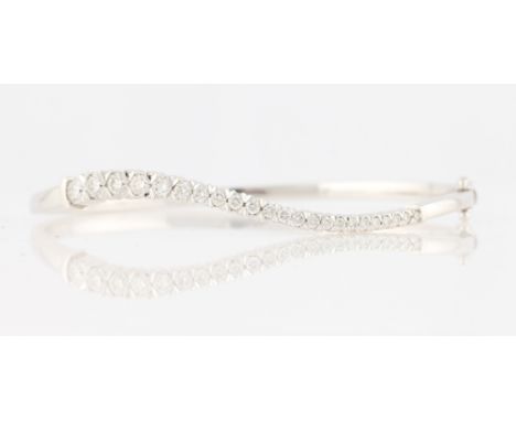 A diamond bangle, the wave design hinged bangle set with a row of 23 round brilliant cut diamonds, the largest measuring appr