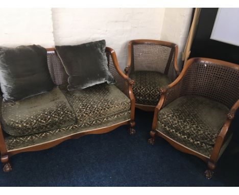 A wicker back sofa with green upholstery and two matching chairs