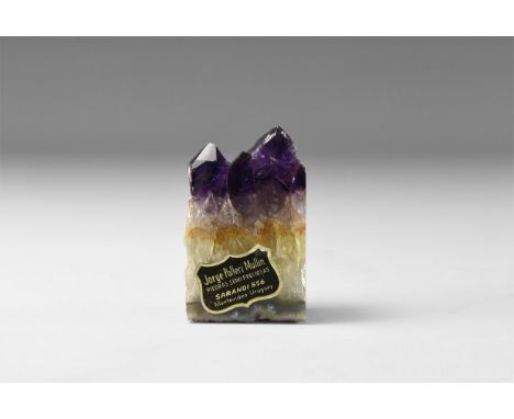 A large cut and polished amethyst geode section with two needles of dark purple with colour paling to clear white agate at th