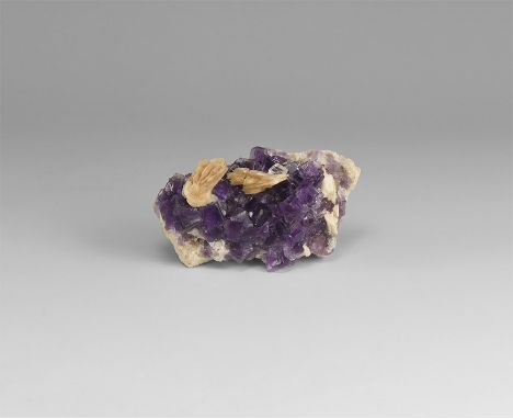 A fine specimen of purple cubic fluorite crystals on a matrix with two barite formations to the top; in a white card box with