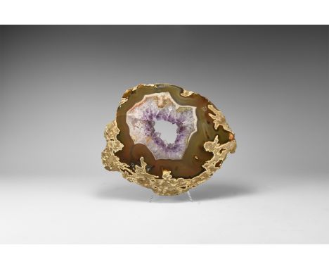 A cut and polished agate geode slice with bands of brown and orange, centre open and the edges framed by clusters of amethyst