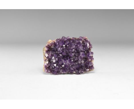 A rectangular panel with dark purple amethyst crystals to one face, in white card tray with label reading: 'AMETHYST, Antigas