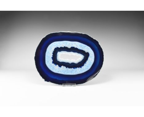 A large cut and polished agate slice with deep blue border and white honeycomb crystals to the centre, colour enhanced. 1.04 